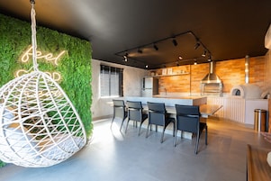 Cozinha moderna com parede verde, luminária pendente e área de bar.