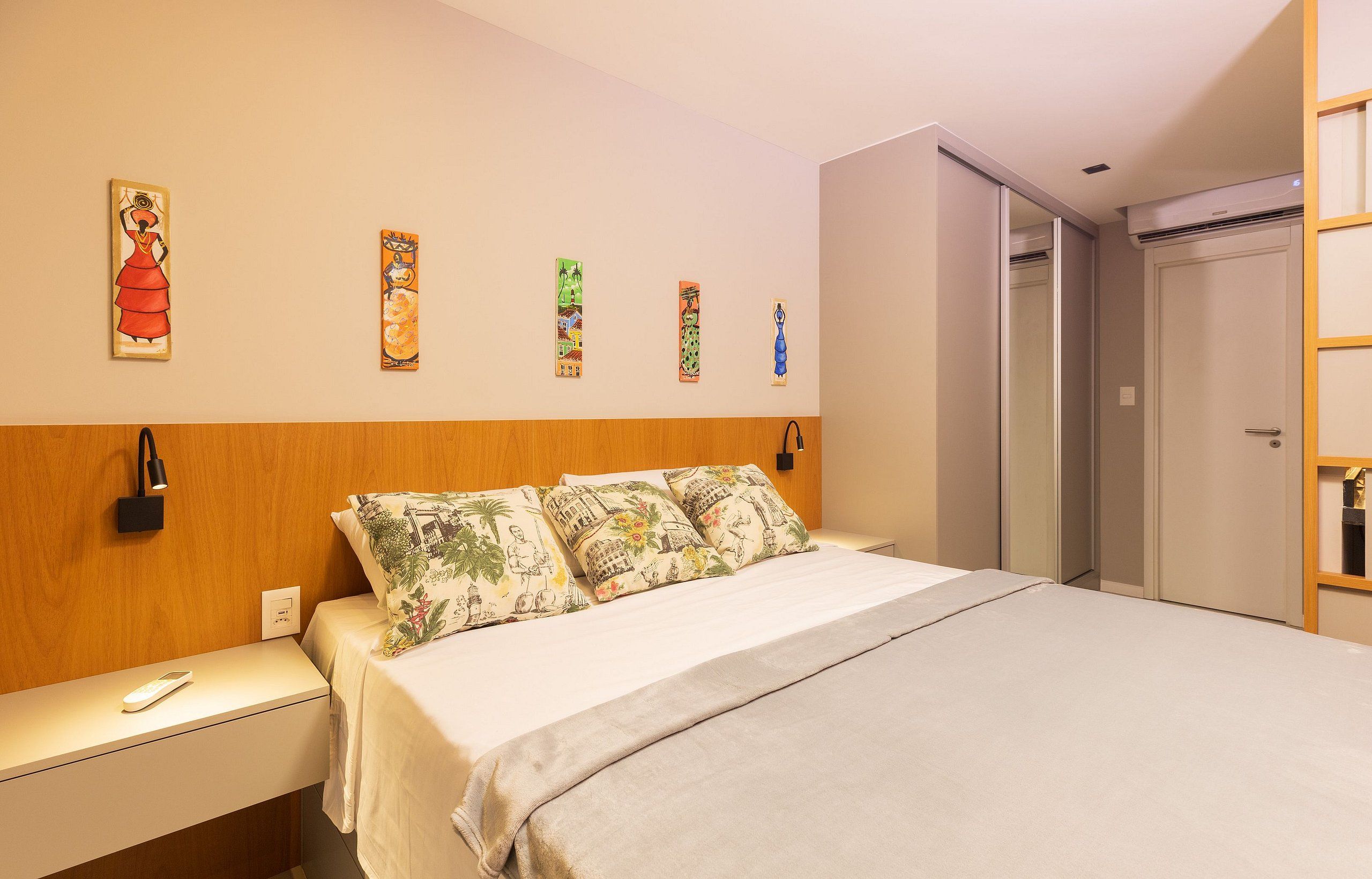 A hotel room with a bed, a nightstand, a wall-mounted lamp, and a wardrobe.