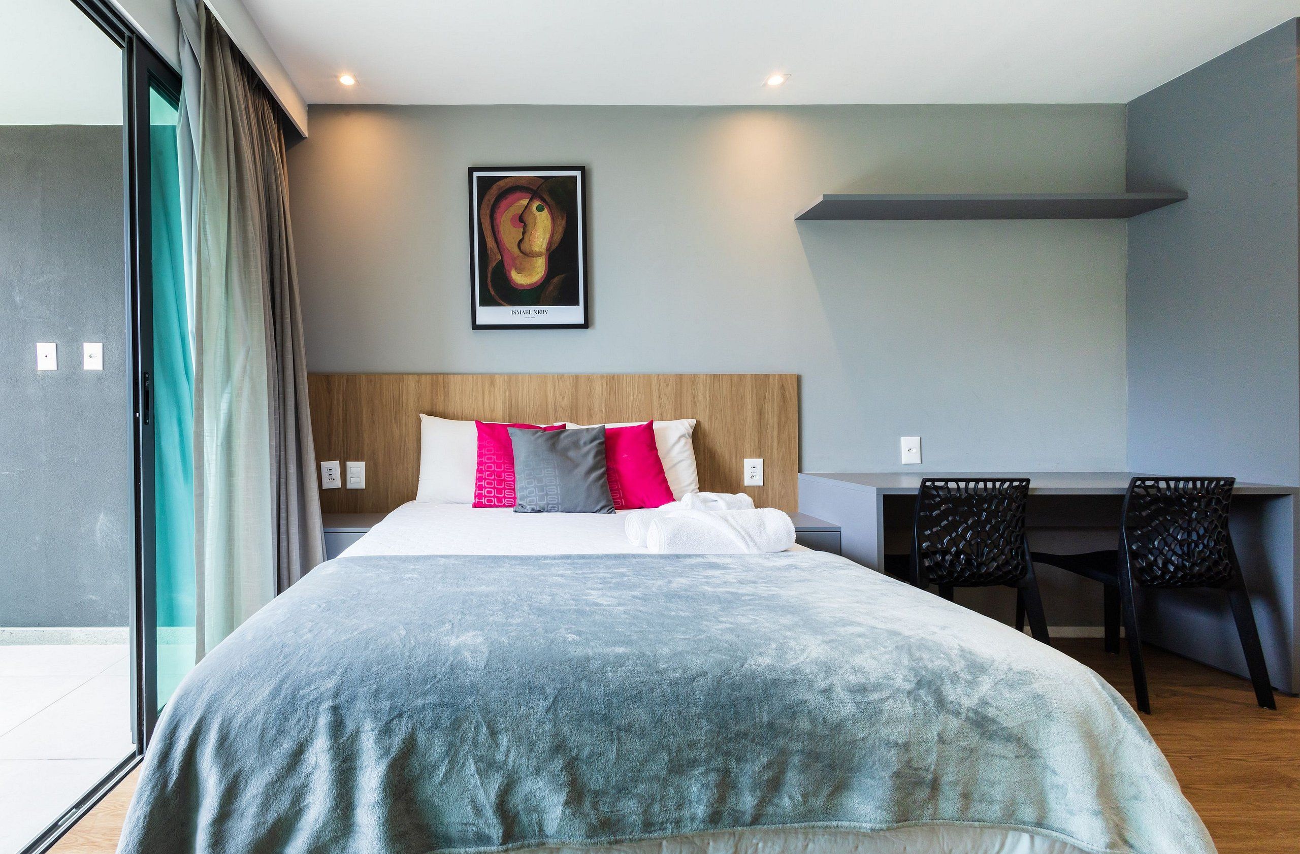 A modern hotel room with a large bed, a desk, and a chair.