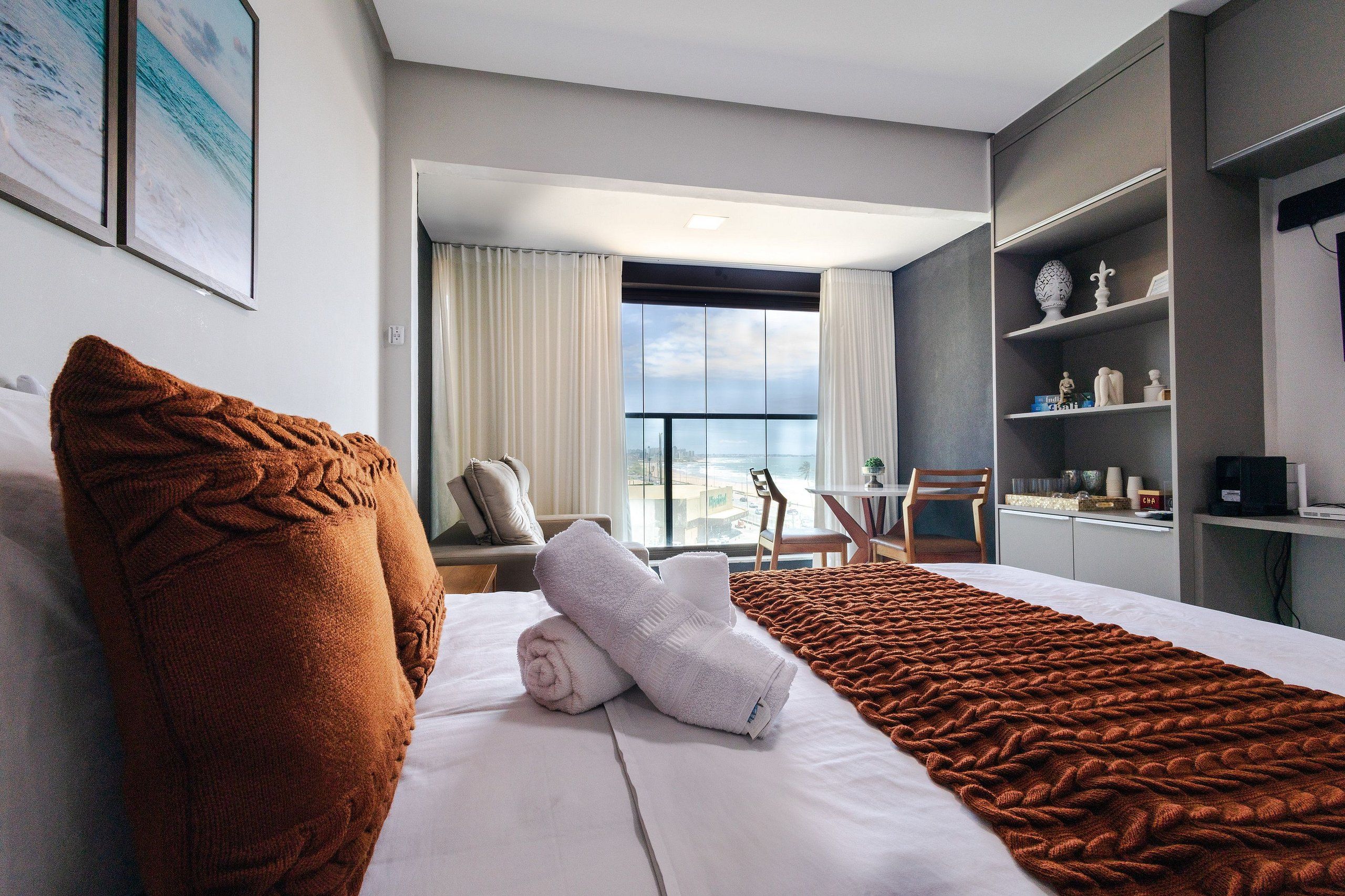 Habitación de hotel con cama, vistas a la ciudad, balcón y escritorio con silla.