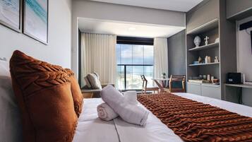 Habitación de hotel con cama, vistas a la ciudad, balcón y escritorio con silla.