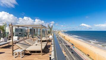 Terraza en la azotea con tumbonas y vista a la playa y al océano.
