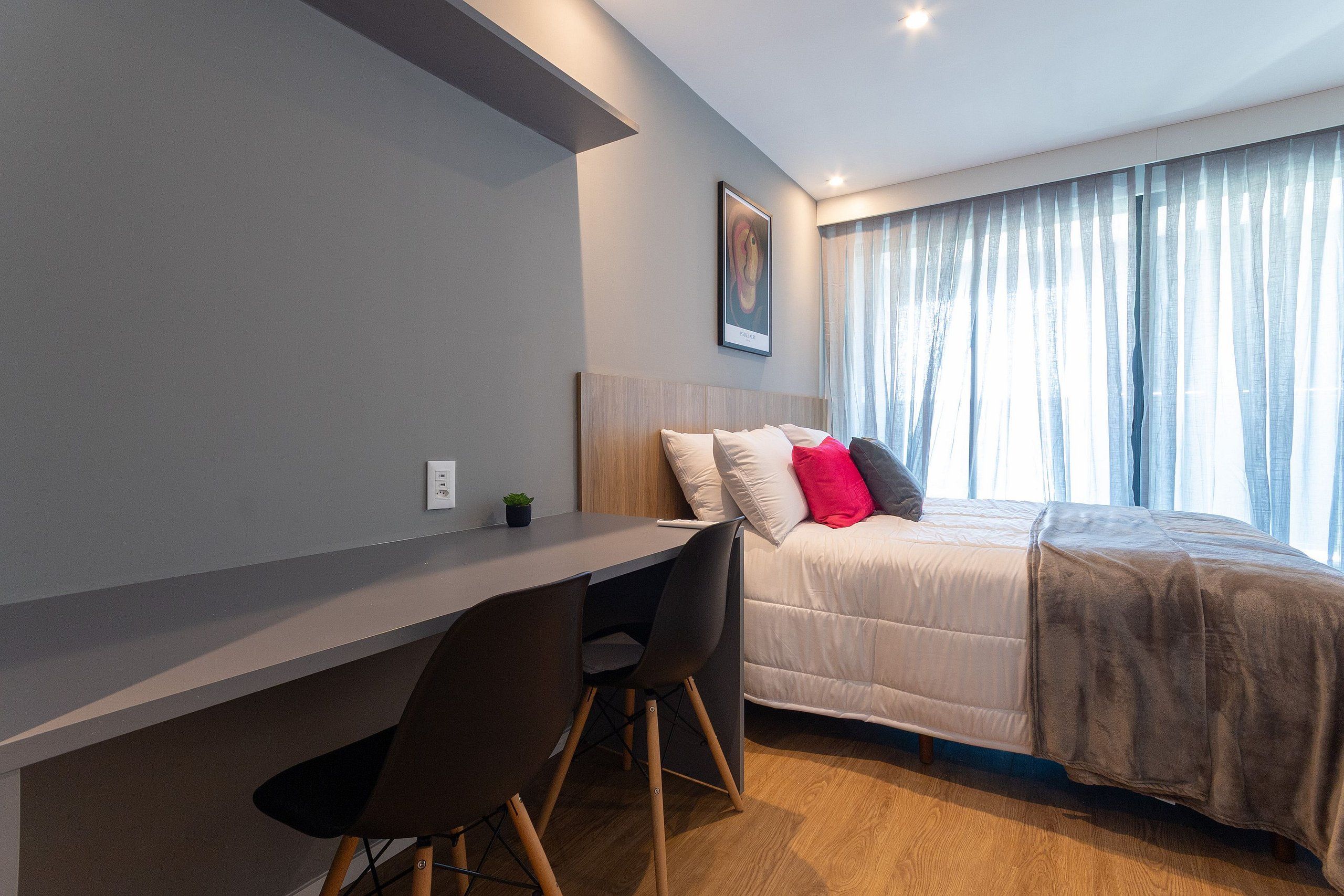 Een moderne slaapkamer met een bed, een bureau en een stoel.