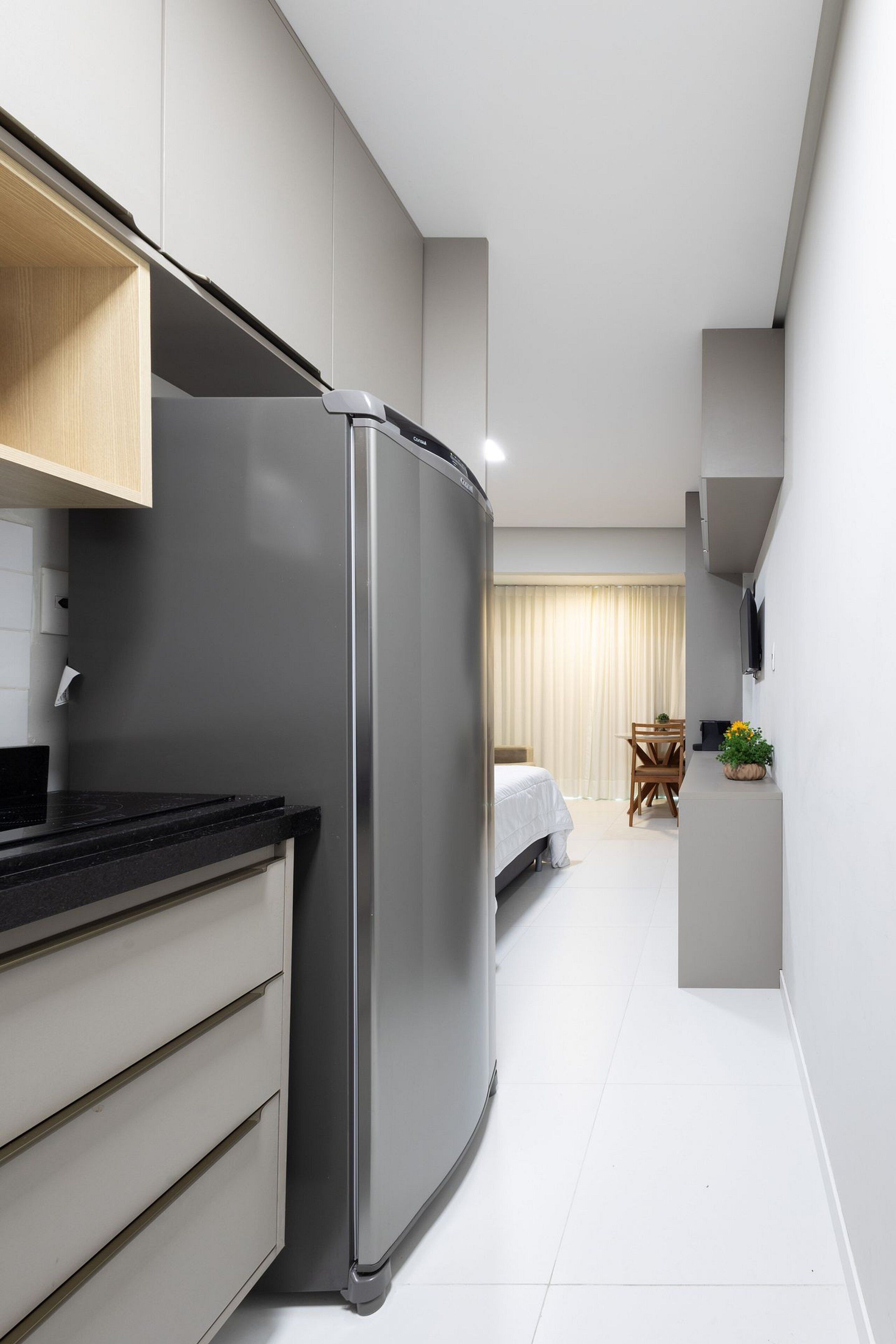 A compact kitchen with a built-in refrigerator, a wooden cabinet, and a dining area with a table and chairs.