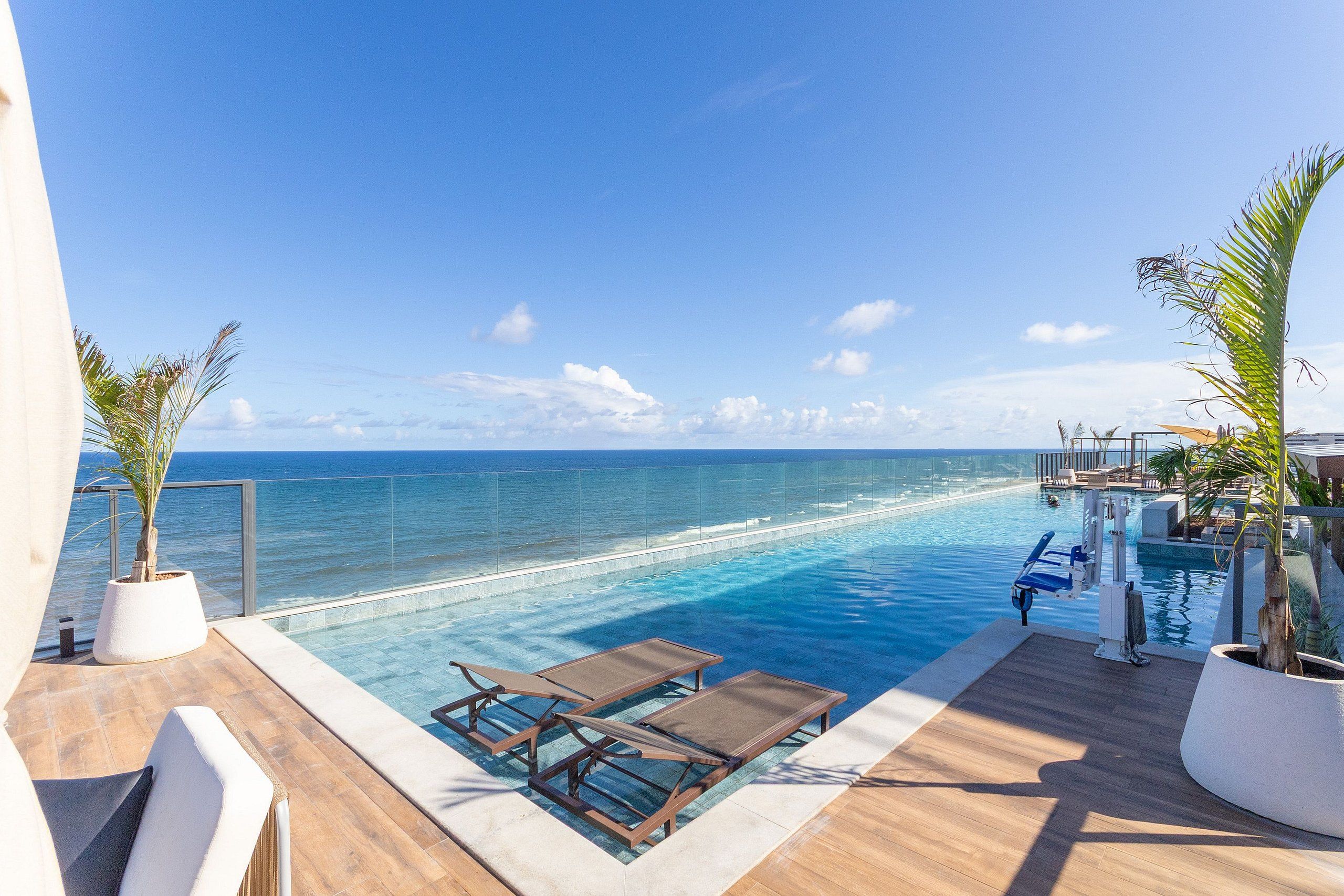 A poolside area with lounge chairs and a view of the ocean.
