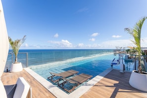 A poolside area with lounge chairs and a view of the ocean. - Art Studio Housi Salvador by Carpediem (Salvador)