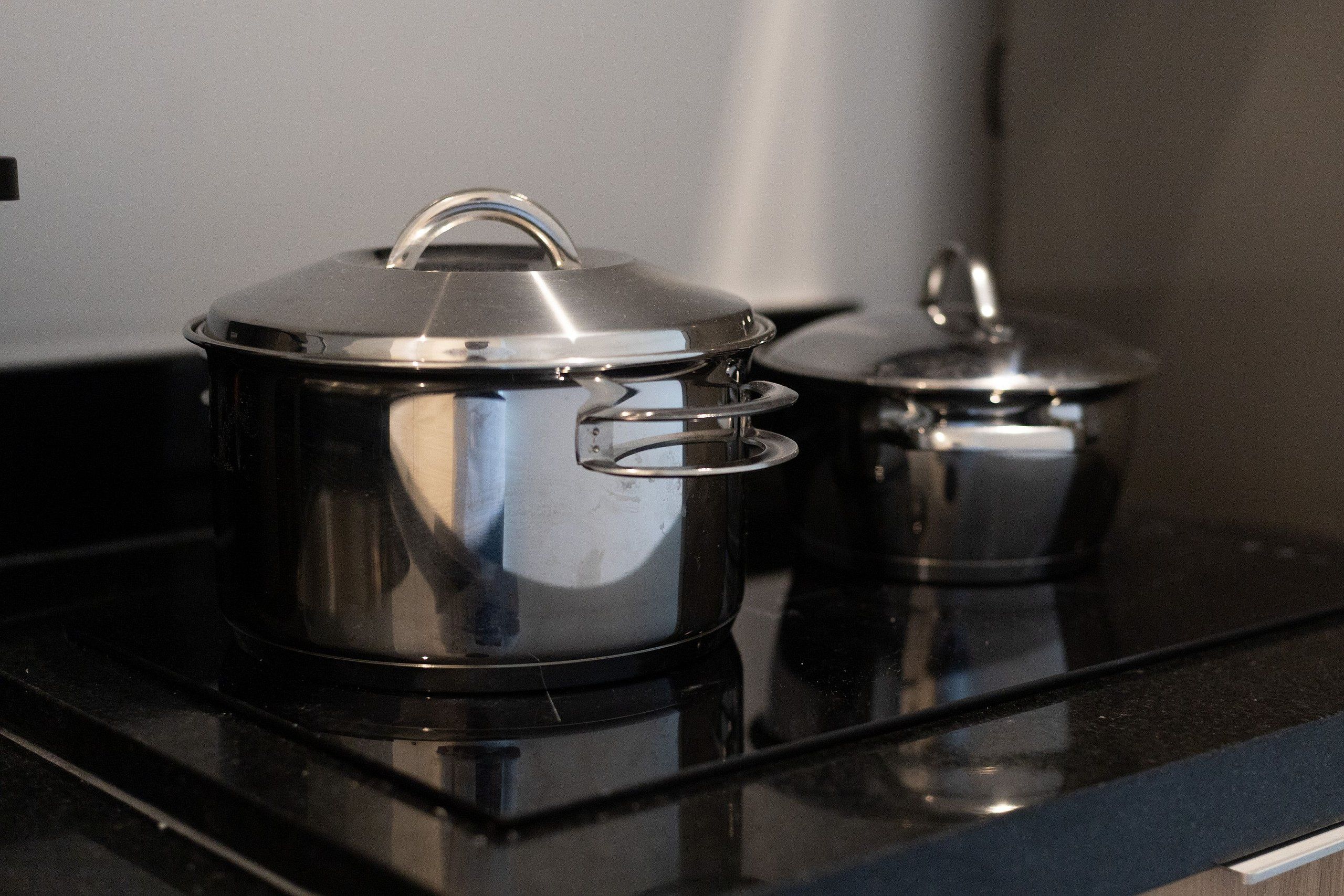 Two stainless steel pots on a black stovetop.