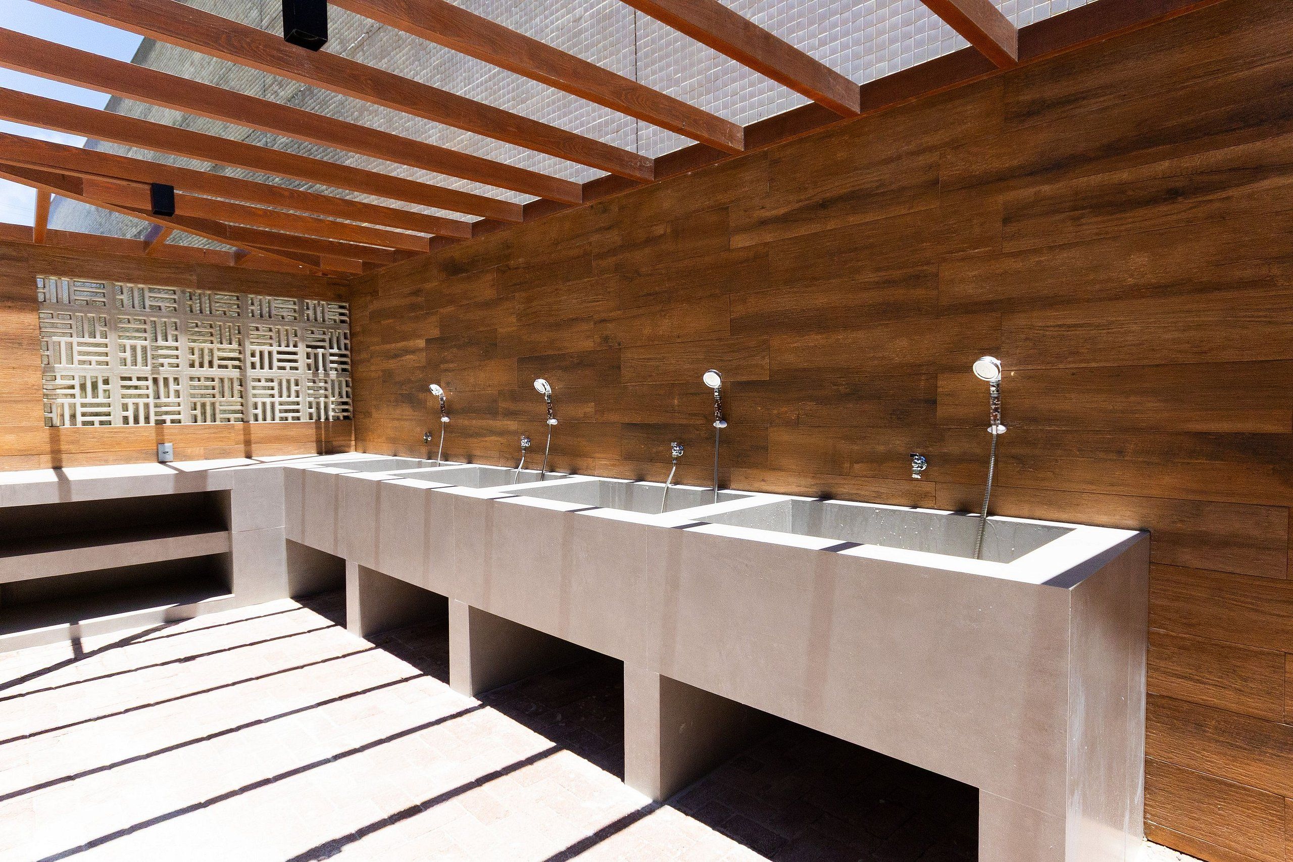 A modern bathroom with multiple sinks, wooden walls, and a sloped ceiling.