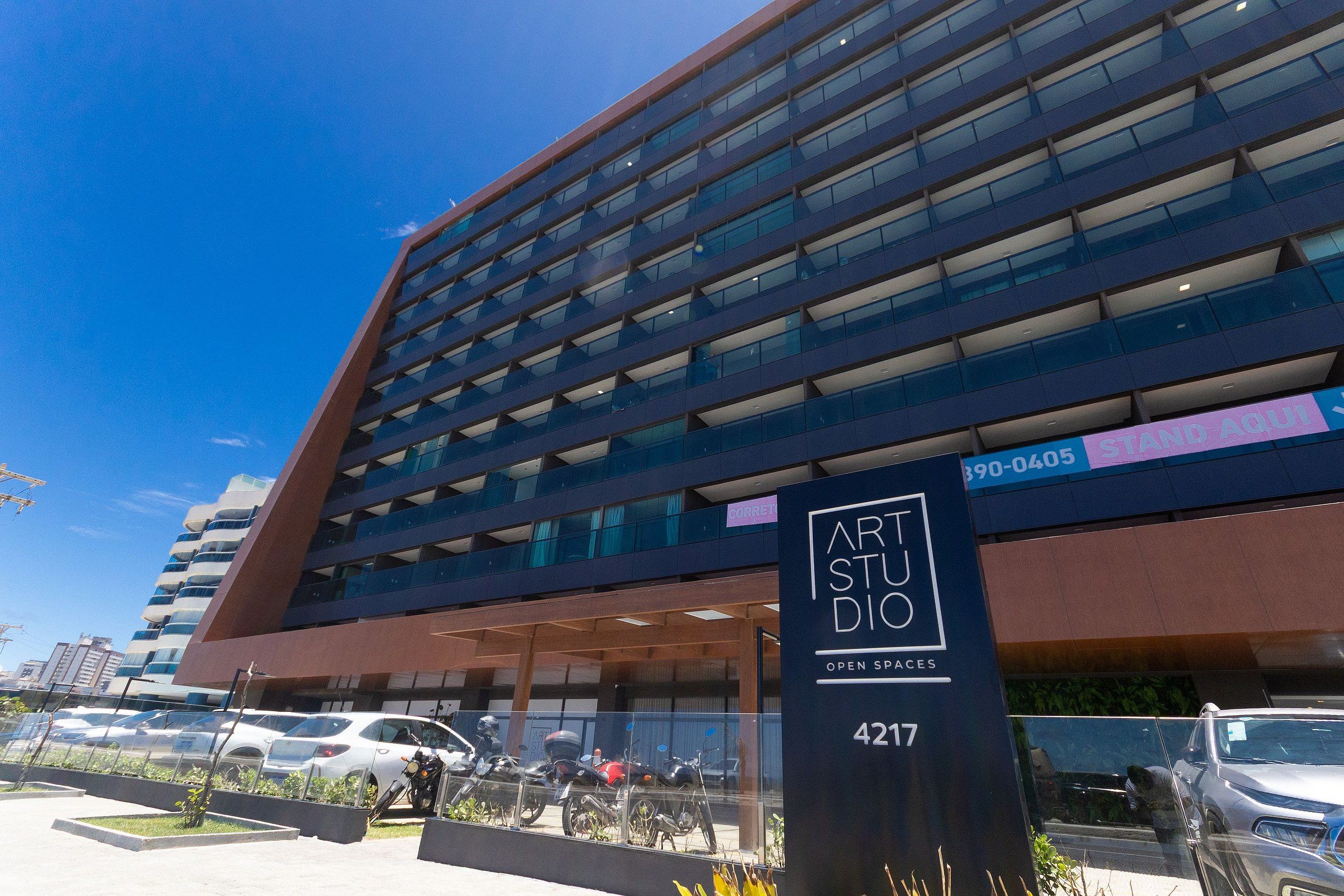 A modern building with a sign for "Art Studio 4217" and a parking area with several cars and motorcycles.