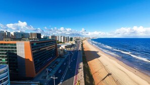 Un paysage urbain côtier avec une vaste plage, des bâtiments modernes et un ciel bleu dégagé.
