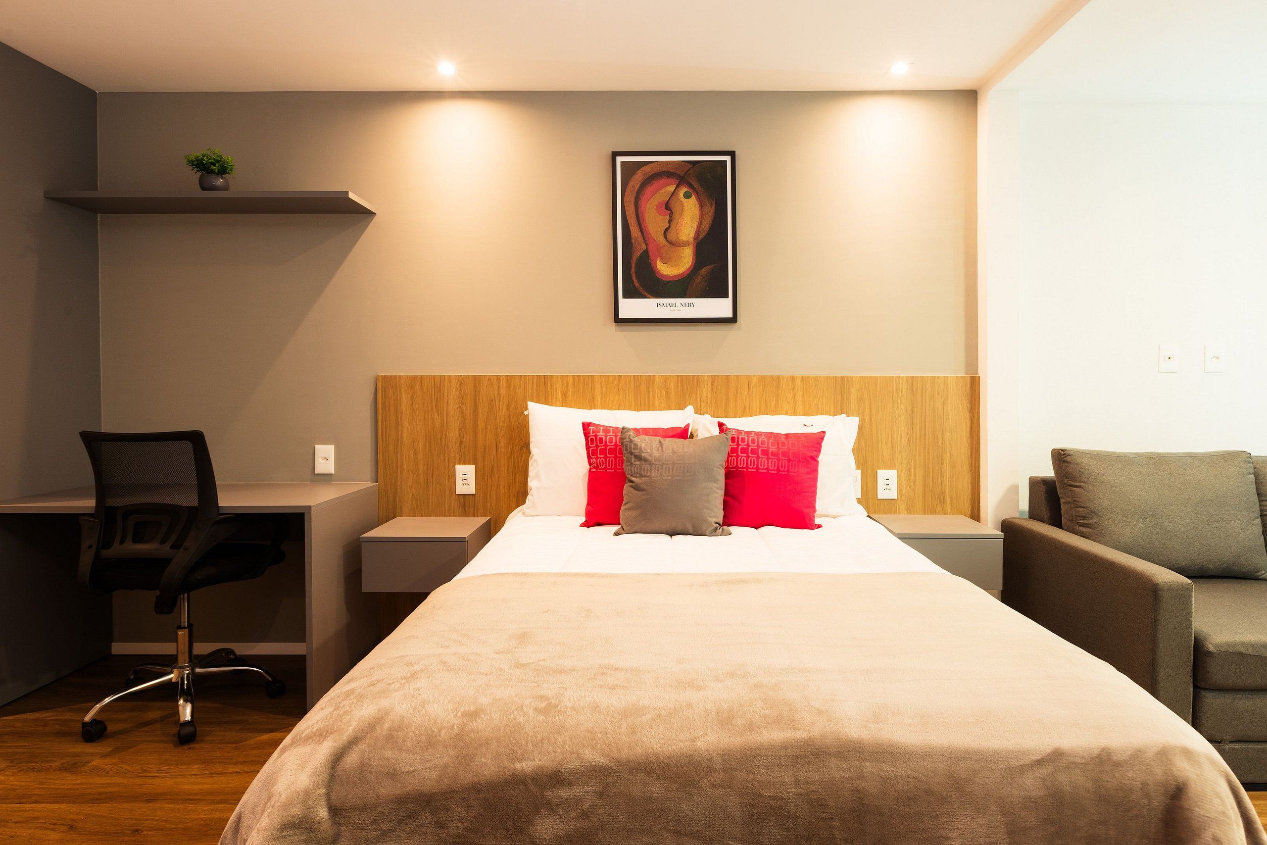 A hotel room with a bed, a desk, a chair, and a couch.