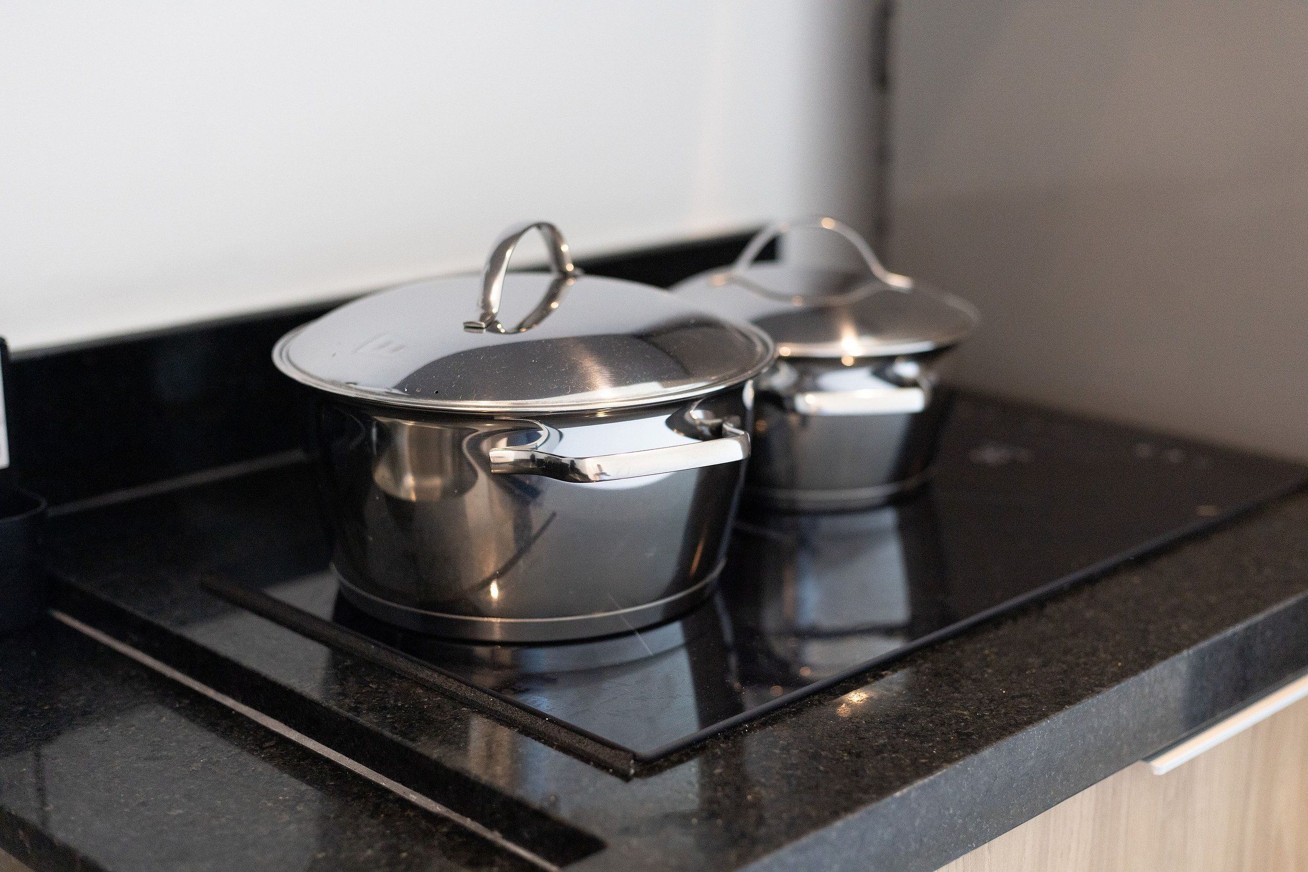 Two stainless steel pots on a black countertop.