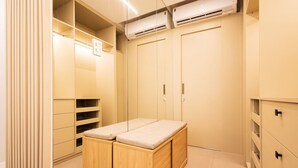 A modern, well-lit walk-in closet with built-in storage, a bench, and an air conditioning unit. - Art Studio Housi Salvador by Carpediem (Salvador)