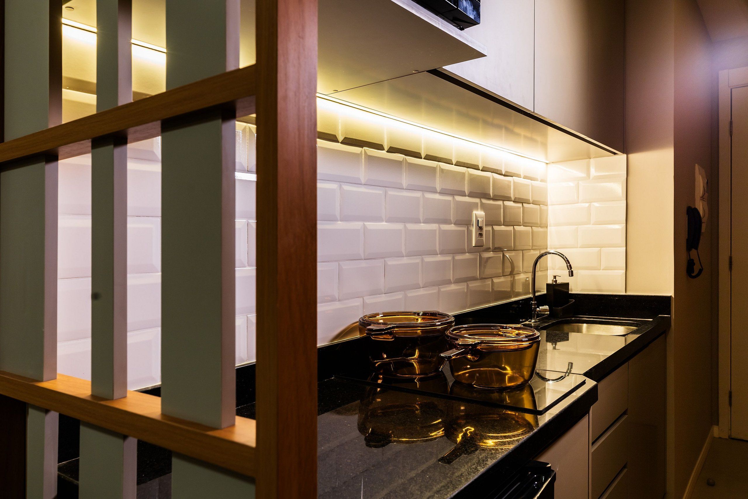 A kitchen with white subway tiles, a black countertop, and a stainless steel sink.