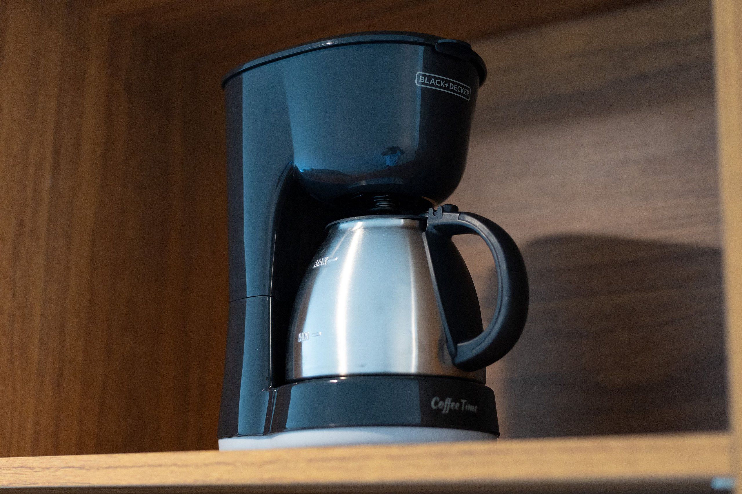 Une machine à café au design noir et argenté, portant l’inscription « Coffee Time », est posée sur une étagère en bois.
