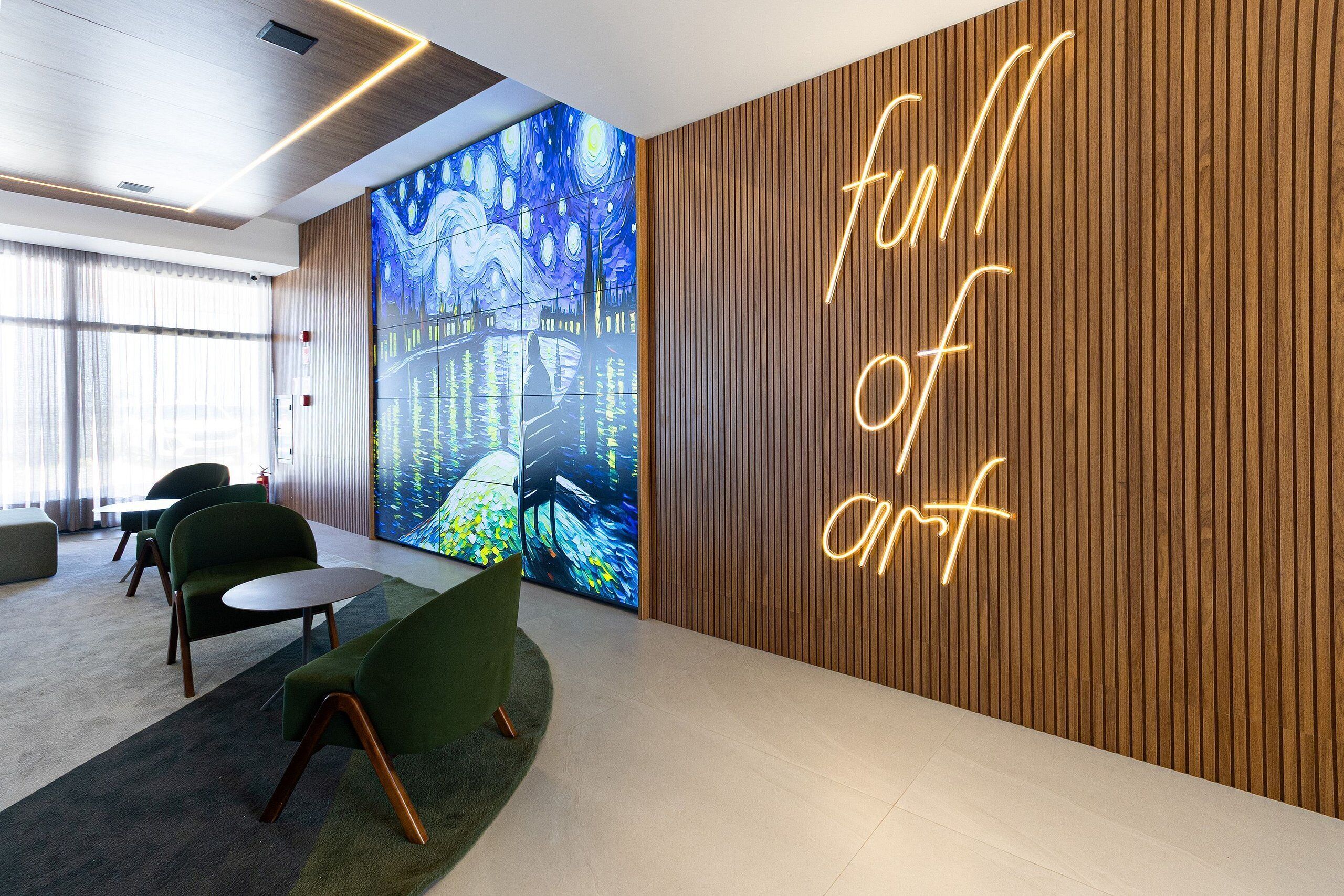 Un hall d’entrée moderne doté d’un grand écran numérique présentant des œuvres d’art, d’un néon affichant l’inscription « plein d’art » et de mobilier contemporain.