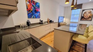 Une cuisine moderne dotée d’un îlot central, d’une machine à café et d’un téléviseur diffusant Netflix.
