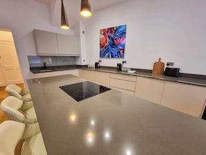 A modern kitchen with a central island, pendant lighting, and a colorful abstract painting. - 2 Bed Altrincham Centre | 2 Bath | Sleeps 6 (Greater Manchester)