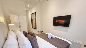 Une chambre d’hôtel avec un lit, des oreillers, une télévision et un miroir fixé au mur.