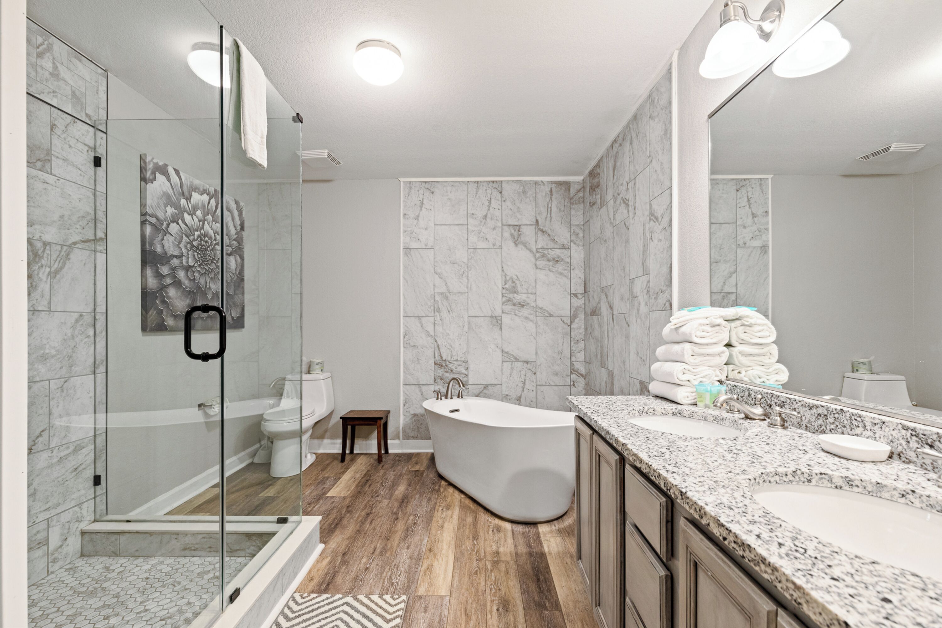 Une salle de bain moderne avec une baignoire sur pieds, une douche à parois de verre et un grand meuble-lavabo avec un miroir.