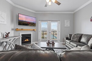 Una sala de estar moderna con chimenea, sofás de cuero, un televisor de pantalla plana y vistas a través de puertas de cristal.