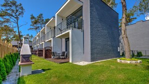 Un bâtiment moderne à deux étages, doté d’un balcon, d’un barbecue et d’une pelouse bien entretenue.