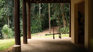 A covered outdoor area with a swing set, surrounded by trees and a dirt path. - Fern House your serene rainforest retreat (Bingil Bay)