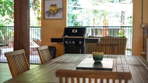 An outdoor patio with a grill, wicker furniture, and a table with a bowl. - Fern House your serene rainforest retreat (Bingil Bay)