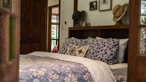 A bed with patterned bedding, a wooden headboard, and a wall with framed pictures.