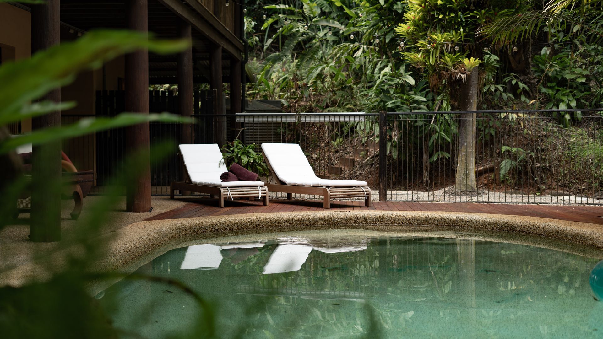 Un área de piscina con dos sillas de descanso y una terraza de madera.