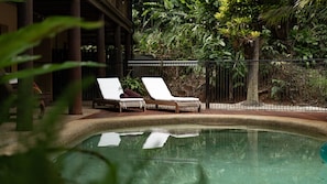 A pool area with two lounge chairs and a wooden deck. - Fern House your serene rainforest retreat (Bingil Bay)