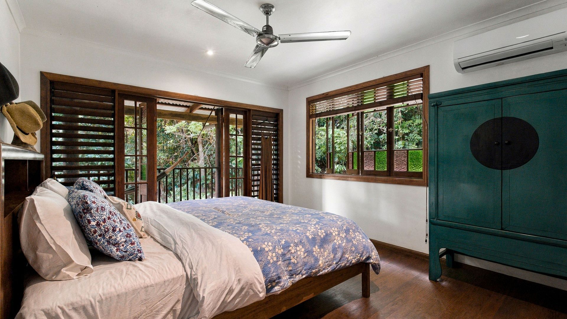 A bedroom with a bed, a ceiling fan, a window with blinds, and a green cabinet.