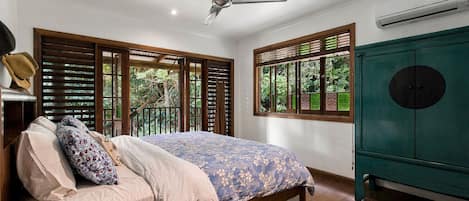 A bedroom with a bed, a ceiling fan, a window with blinds, and a green cabinet.