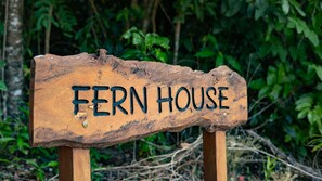 A rustic wooden sign with the words 'FERN HOUSE' carved into it. - Fern House your serene rainforest retreat (Bingil Bay)