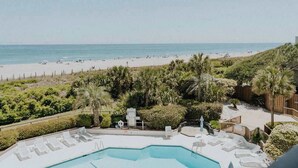 A pool area with lounge chairs and a view of the beach. - The Spoleto by Mira-Mar (Wrightsville Beach)
