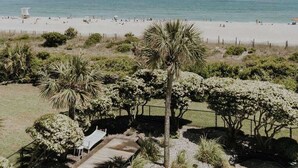A beach view with a pathway leading to a seating area with chairs and a table. - The Spoleto by Mira-Mar (Wrightsville Beach)
