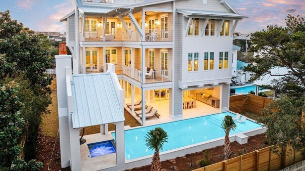 Une grande maison à plusieurs étages, dotée d’une piscine, de nombreux balcons et d’un patio couvert.