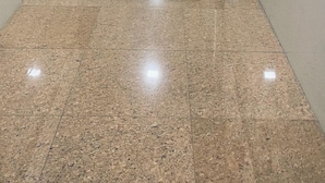 Un lungo corridoio ben illuminato con pavimento in piastrelle lucide e un estintore montato sulla parete.