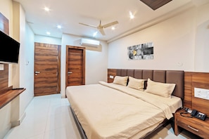 Une chambre d’hôtel moderne dotée d’un grand lit, d’une table de chevet, d’un ventilateur de plafond, d’un climatiseur et d’un téléviseur fixé au mur.