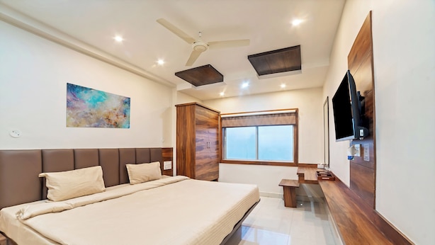 Una camera da letto moderna con un letto grande, un ventilatore a soffitto, una TV a parete e una finestra con vista.