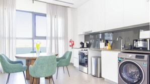 A modern kitchen with a dining area, stainless steel appliances, and a washing machine. - Bloomfields Modern STU Pixel Beach Acces (Abu Dhabi)