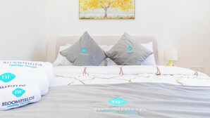 A hotel room with a bed, pillows, a painting of a tree, and a lamp. - Bloomfields Modern STU Pixel Beach Acces (Abu Dhabi)
