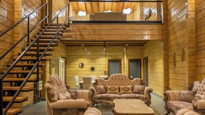 A spacious interior with a wooden staircase, a second-floor balcony, and a seating area with ornate furniture. - Villa 199 Amarja's Sunset Retreat (Mawal)