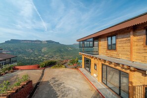 A modern wooden building with large windows and a balcony overlooking a mountainous landscape. - Villa 199 Amarja's Sunset Retreat (Mawal)