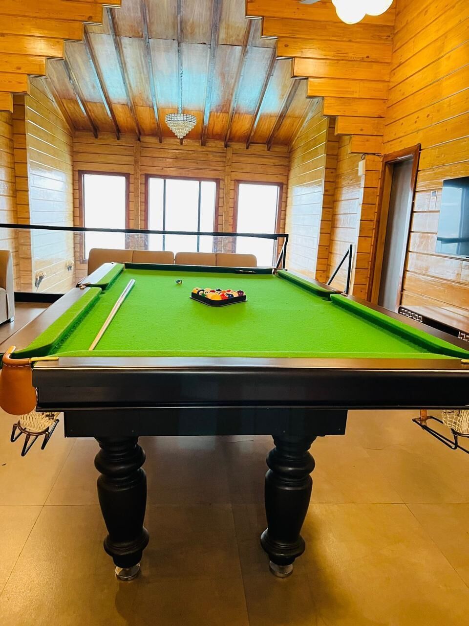 Ein Billardtisch mit grüner Spielbahn, schwarzen Beinen und einem weißen Mittelball.
