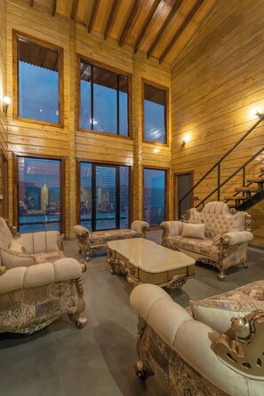 A spacious room with high ceilings and large windows, featuring ornate furniture and a staircase. - Villa 199 Amarja's Sunset Retreat (Mawal)