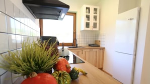 A modern kitchen with white cabinets, a black range hood, and a wooden countertop. - Holiday Home in Dabie, Directly at the Lake (Bytow)
