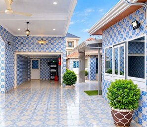 A hotel corridor with patterned walls and tiled flooring, leading to a reception area with a fire extinguisher and a potted plant. - A charming apartment in the annex for a peaceful stay (Conakry)
