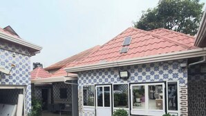 Une maison à deux étages avec un patio carrelé, un toit rouge et des murs décorés de motifs.