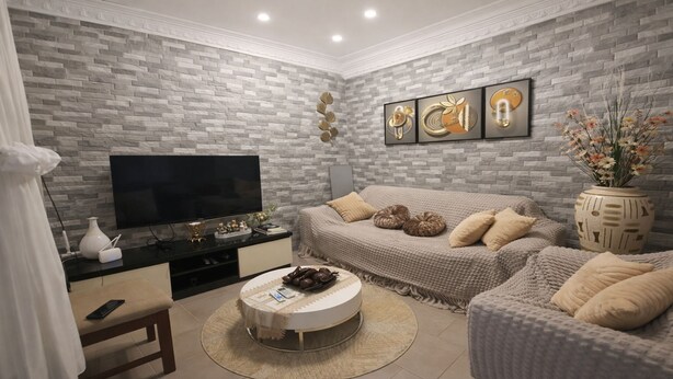 Un salon avec un mur décoré d’un motif en briques, un téléviseur à écran plat, un canapé, une table basse et un vase décoratif avec des fleurs.